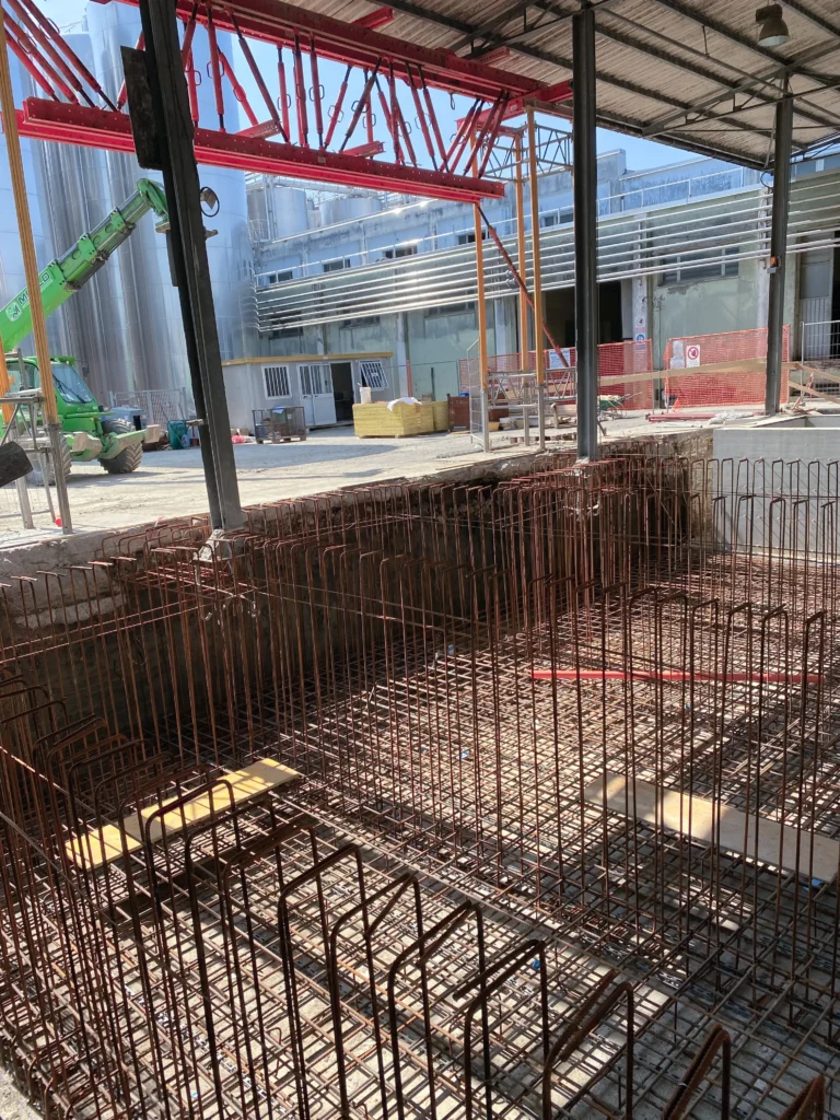 Cantiere per impianto industriale con silos di stoccaggio e area produttiva in costruzione realizzato da Impref